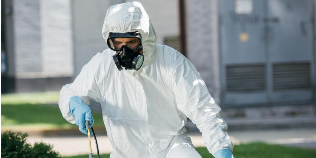 Pest control technician wearing respirators and coveralls
